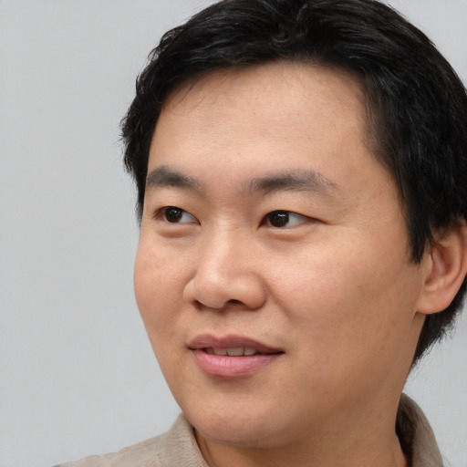 Joyful asian young-adult male with short  brown hair and brown eyes