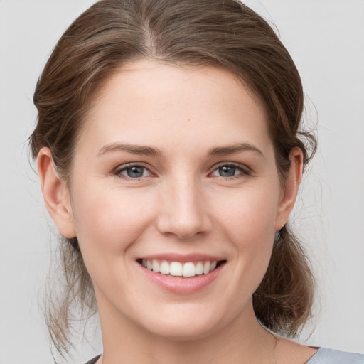 Joyful white young-adult female with medium  brown hair and grey eyes