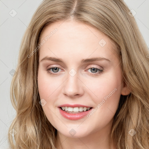 Joyful white young-adult female with long  brown hair and blue eyes