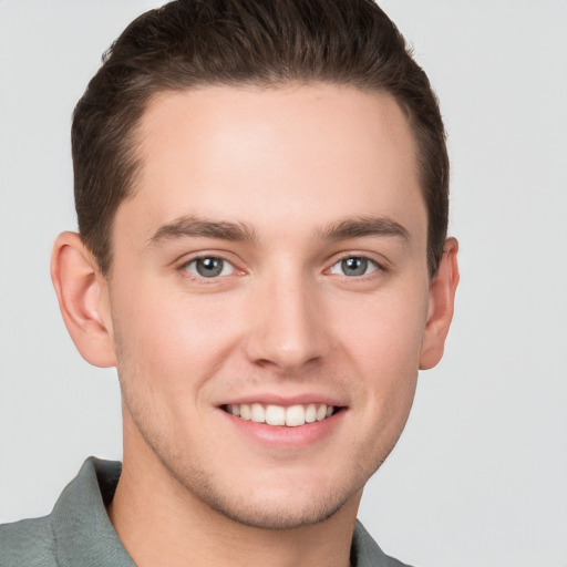 Joyful white young-adult male with short  brown hair and grey eyes