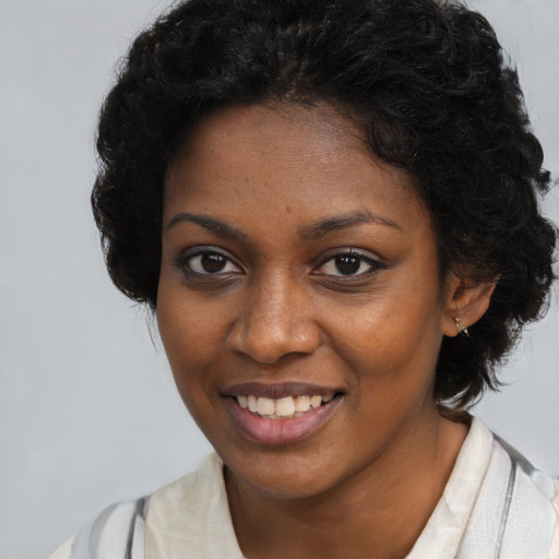 Joyful black young-adult female with short  black hair and brown eyes