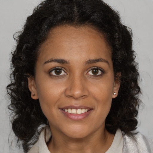 Joyful black young-adult female with long  brown hair and brown eyes