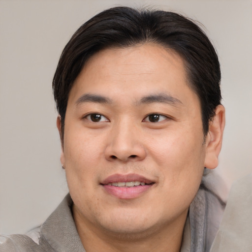 Joyful asian young-adult male with short  brown hair and brown eyes