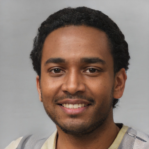 Joyful black young-adult male with short  black hair and brown eyes