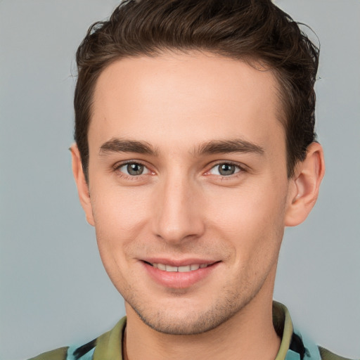 Joyful white young-adult male with short  brown hair and grey eyes