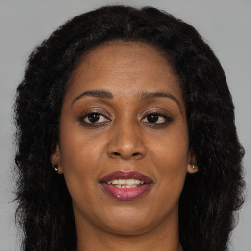 Joyful black adult female with long  brown hair and brown eyes