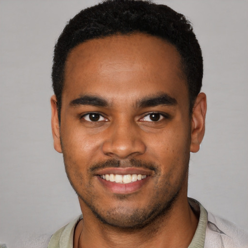 Joyful black young-adult male with short  brown hair and brown eyes