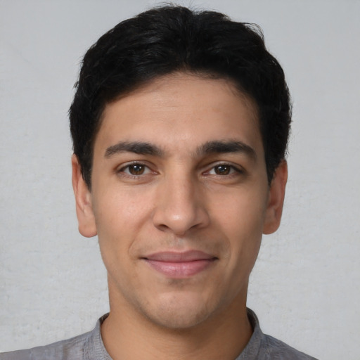 Joyful latino young-adult male with short  black hair and brown eyes