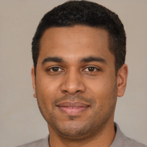 Joyful black young-adult male with short  brown hair and brown eyes