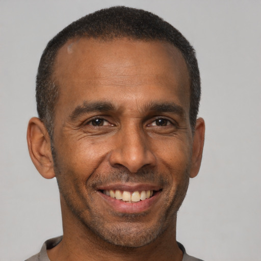 Joyful black adult male with short  black hair and brown eyes