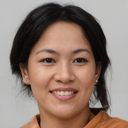 Joyful asian adult female with medium  brown hair and brown eyes