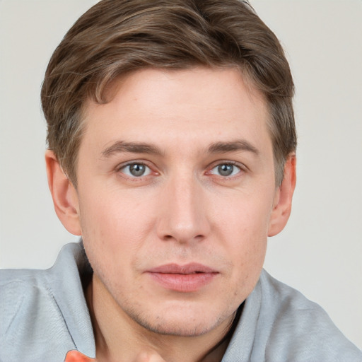 Joyful white young-adult male with short  brown hair and grey eyes