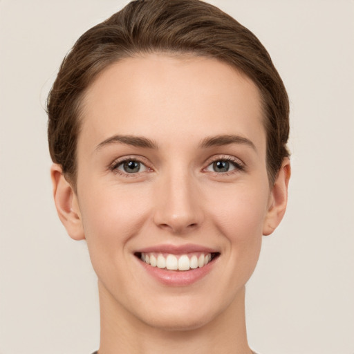 Joyful white young-adult female with short  brown hair and grey eyes