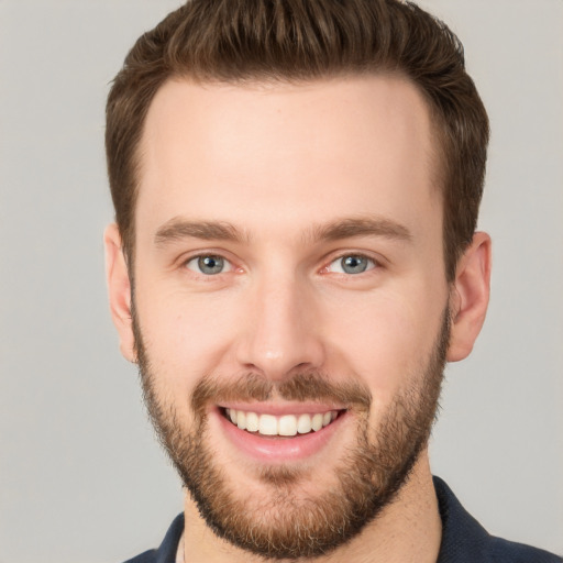 Joyful white young-adult male with short  brown hair and grey eyes