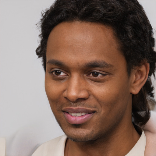 Joyful black young-adult male with short  brown hair and brown eyes