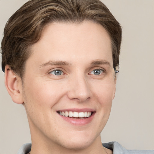 Joyful white young-adult male with short  brown hair and grey eyes