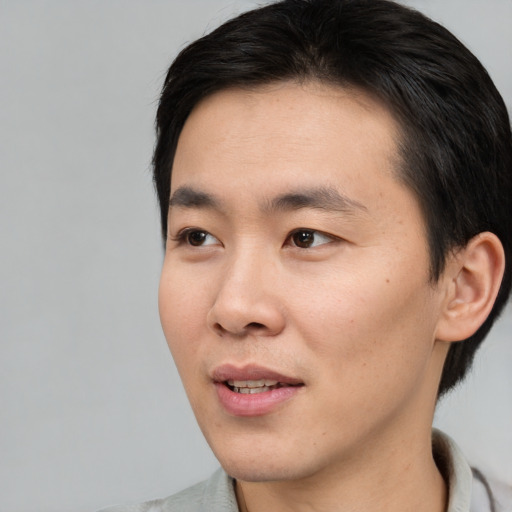 Joyful asian young-adult male with short  brown hair and brown eyes
