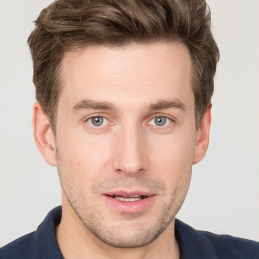 Joyful white young-adult male with short  brown hair and grey eyes