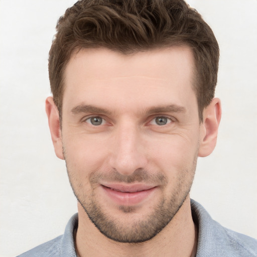 Joyful white young-adult male with short  brown hair and grey eyes