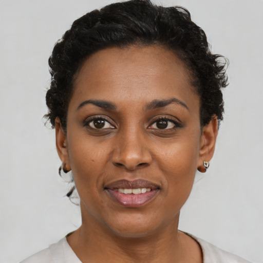 Joyful black young-adult female with short  black hair and brown eyes