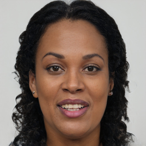 Joyful black young-adult female with long  brown hair and brown eyes