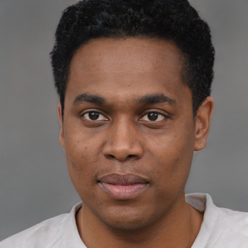 Joyful black young-adult male with short  black hair and brown eyes