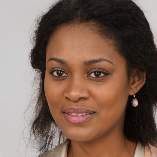 Joyful black young-adult female with long  brown hair and brown eyes