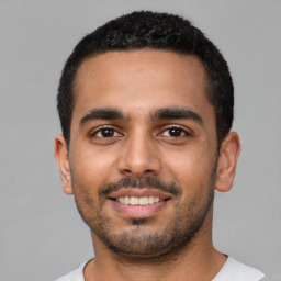 Joyful latino young-adult male with short  black hair and brown eyes