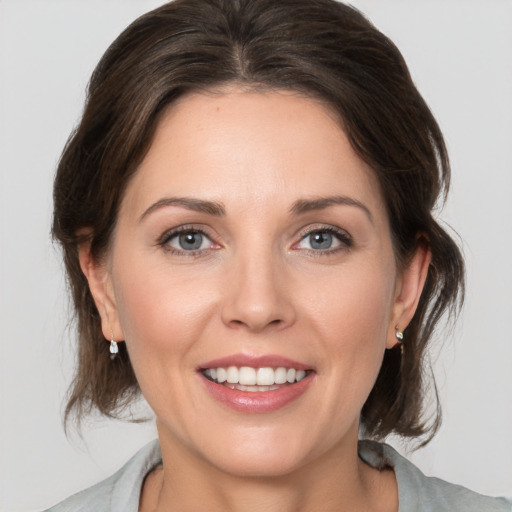 Joyful white young-adult female with medium  brown hair and grey eyes