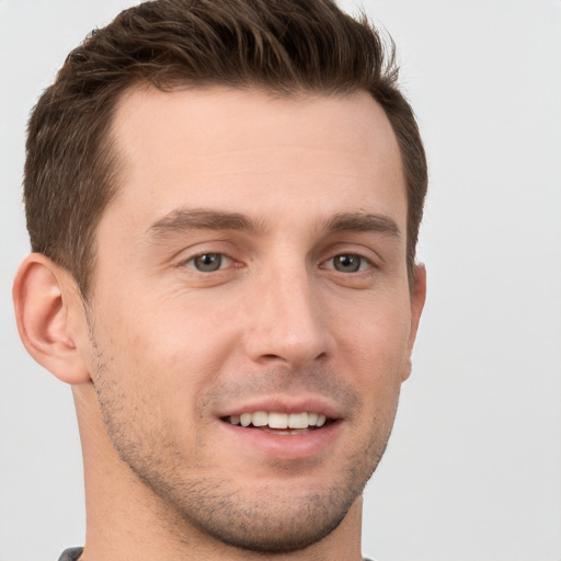 Joyful white young-adult male with short  brown hair and grey eyes