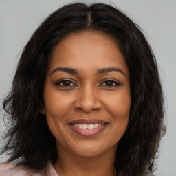 Joyful black young-adult female with long  brown hair and brown eyes