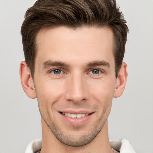 Joyful white young-adult male with short  brown hair and grey eyes