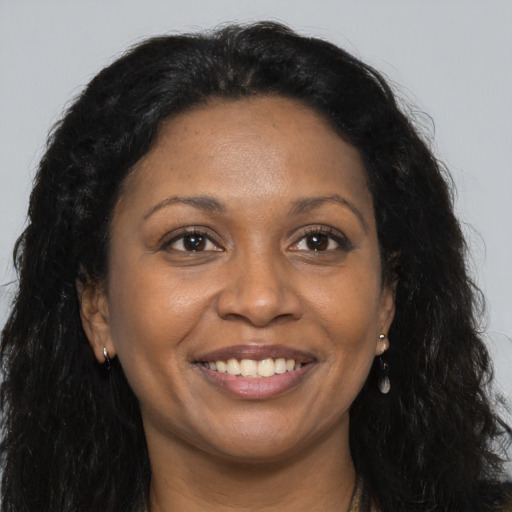 Joyful black adult female with long  brown hair and brown eyes