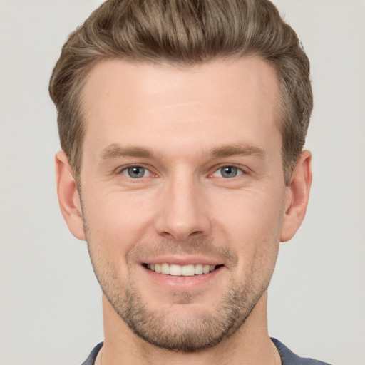 Joyful white young-adult male with short  brown hair and grey eyes