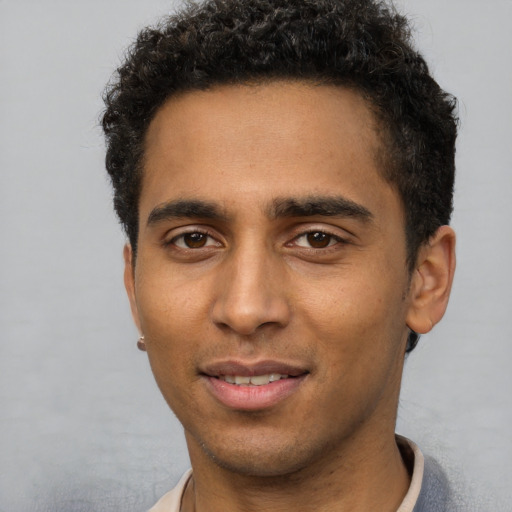 Joyful black young-adult male with short  brown hair and brown eyes