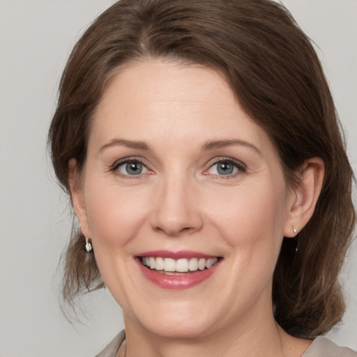 Joyful white young-adult female with medium  brown hair and grey eyes