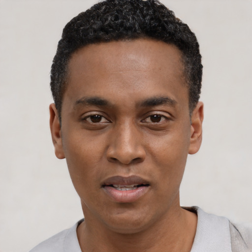 Joyful black young-adult male with short  black hair and brown eyes