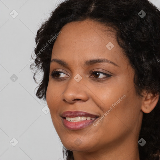 Joyful black young-adult female with long  black hair and brown eyes