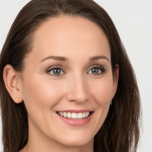 Joyful white young-adult female with long  brown hair and grey eyes