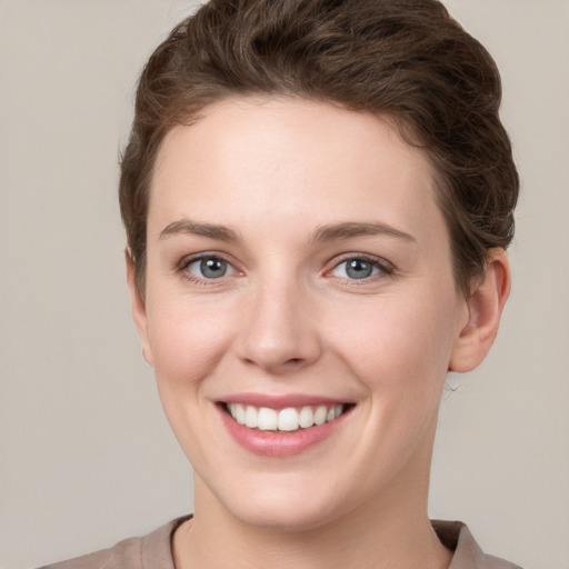 Joyful white young-adult female with short  brown hair and grey eyes