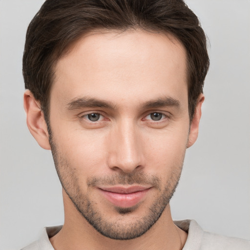 Joyful white young-adult male with short  brown hair and grey eyes