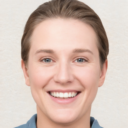 Joyful white young-adult female with short  brown hair and grey eyes