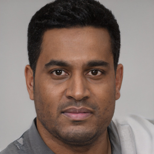 Joyful black young-adult male with short  black hair and brown eyes