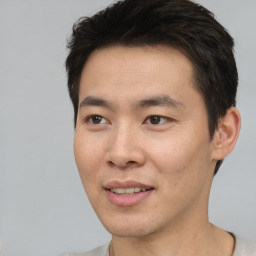 Joyful asian young-adult male with short  brown hair and brown eyes