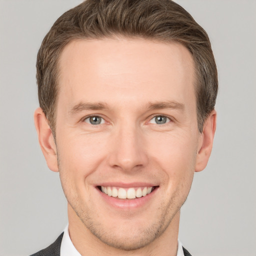 Joyful white young-adult male with short  brown hair and grey eyes