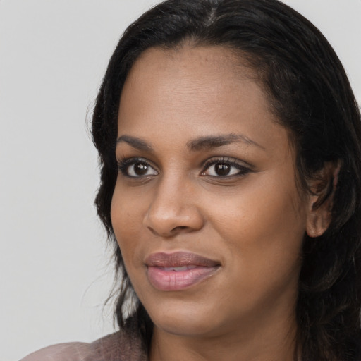 Joyful black young-adult female with long  black hair and brown eyes