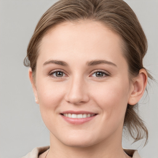 Joyful white young-adult female with medium  brown hair and grey eyes