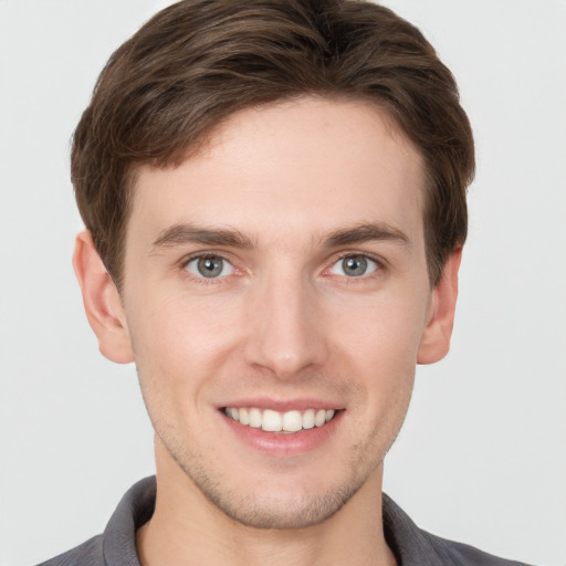 Joyful white young-adult male with short  brown hair and grey eyes