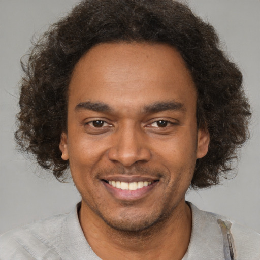 Joyful black young-adult male with short  brown hair and brown eyes