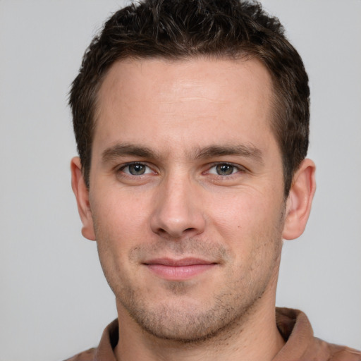 Joyful white young-adult male with short  brown hair and grey eyes